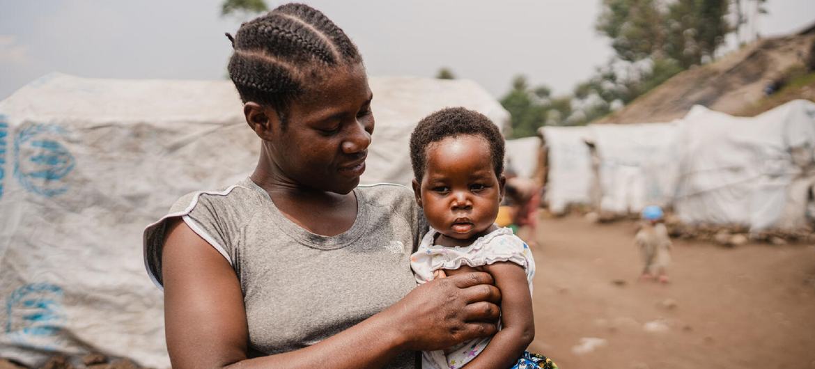 A mother holds her young child after having visited a UN-supported medical clinic at an IDP camp in North Kivu.