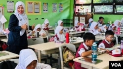 Children eat a free meal at school. (Devianti Faridz/VOA)