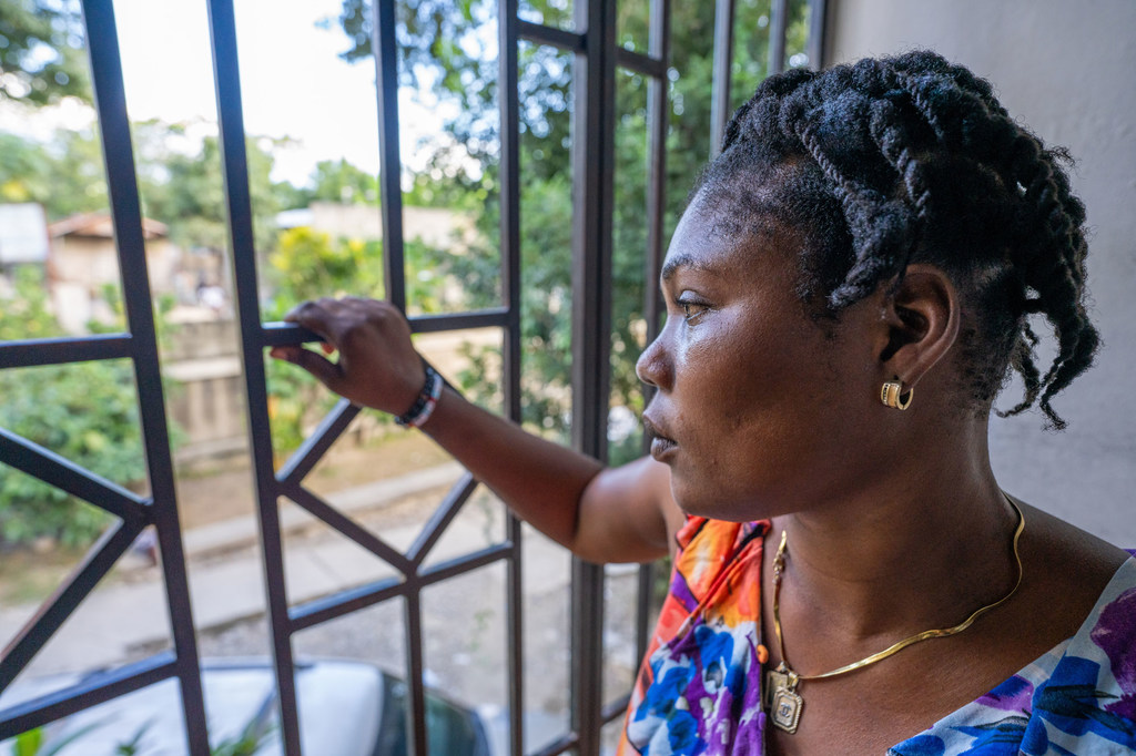 Mireille gazes through the protective bars at the GARR facility, reflecting on her journey back to Haiti.