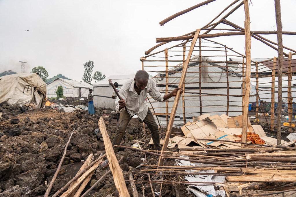 A man dismantles his shelter in a camp before leaving for a safer location.