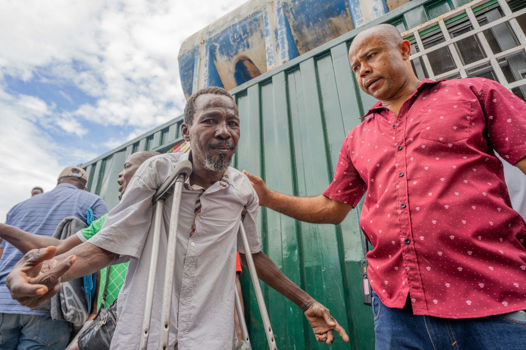 An IOM staff member greets displaced people at an aid distribution site.