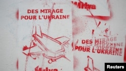 FILE - Graffiti highlighting the announcement that French President Emmanuel Macron has promised to supply Ukraine with Mirage 2000-5 fighter jets is painted on the wall, in Paris, France, June 24, 2024. The graffiti reads “Mirage fighter jets for Ukraine.”