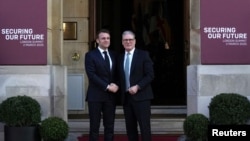 British Prime Minister Keir Starmer shakes hands with French President Emmanuel Macron as he arrives for a summit on Ukraine at Lancaster House in London, March 2, 2025.