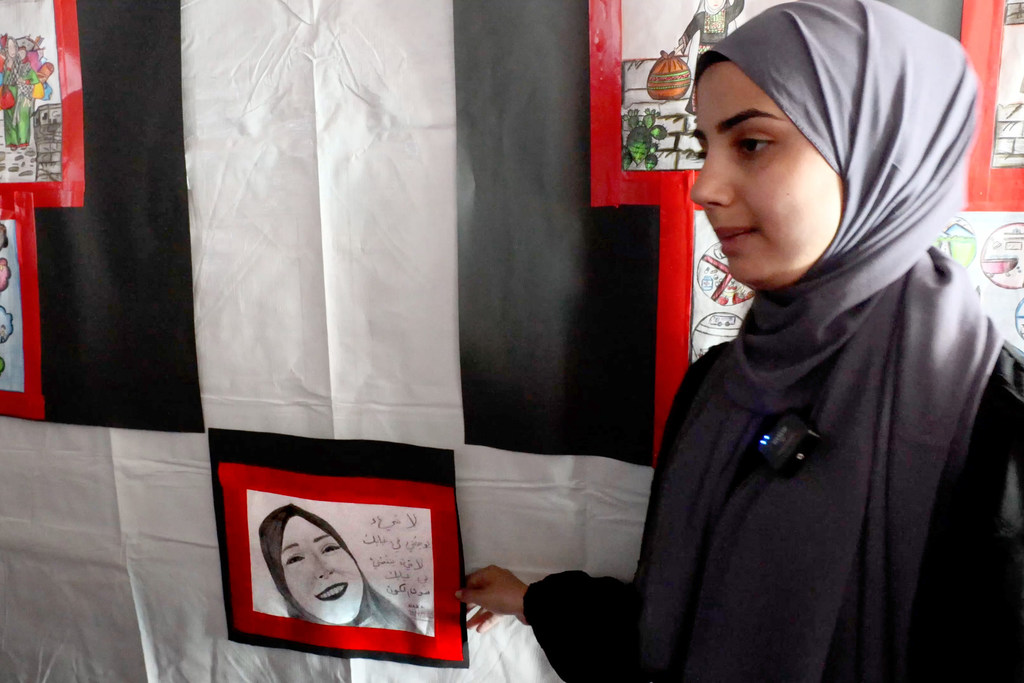 17 year-old Na’emat Haboob, the sole survivor of her family and displaced from Jabalia Camp, stands beside her artwork—a moving tribute to her mother, who was killed in the war. 17 year-old Na’emat Haboob, the sole survivor of her family and displaced from Jabalia Camp, stands beside her artwork—a moving tribute to her mother, who was killed in the war.